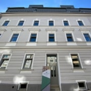 Außenansicht der grauen Fassade aus der Perspektive eines Fußgängers.