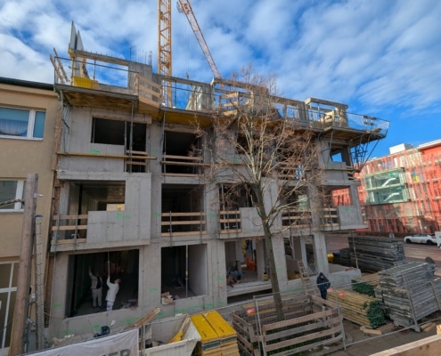 Das Eckhaus ist im Rohbau. Man sieht Menschen, die dort arbeiten.