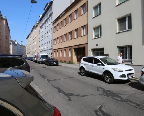 Hier sieht man in einer Häuserreihe ein Haus mit brauner Fassade.