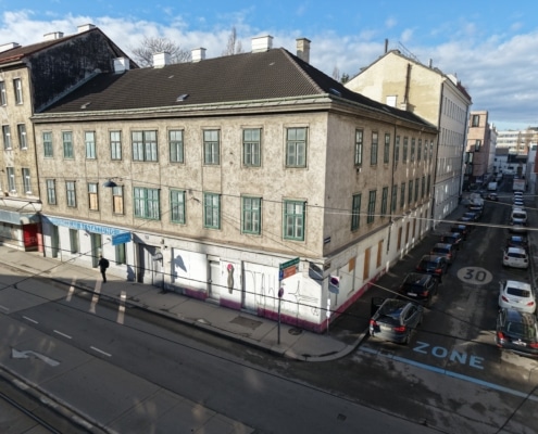 Gründerzeithaus mit bräunlicher Fassade das saniert und aufgestockt wird.