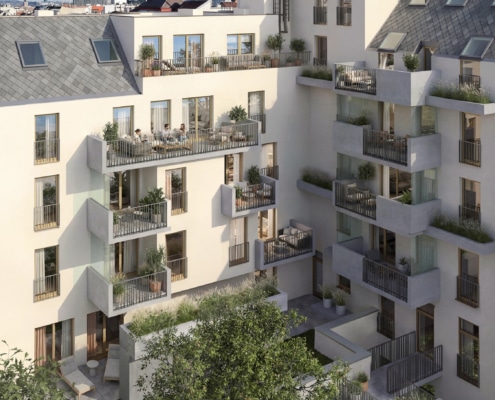 Hier sieht man den Innenhof eines sanierten Hauses mit heller Fassade. Auf den Balkonen sitzen Menschen. Im Garten sieht man die grüne Wiese.